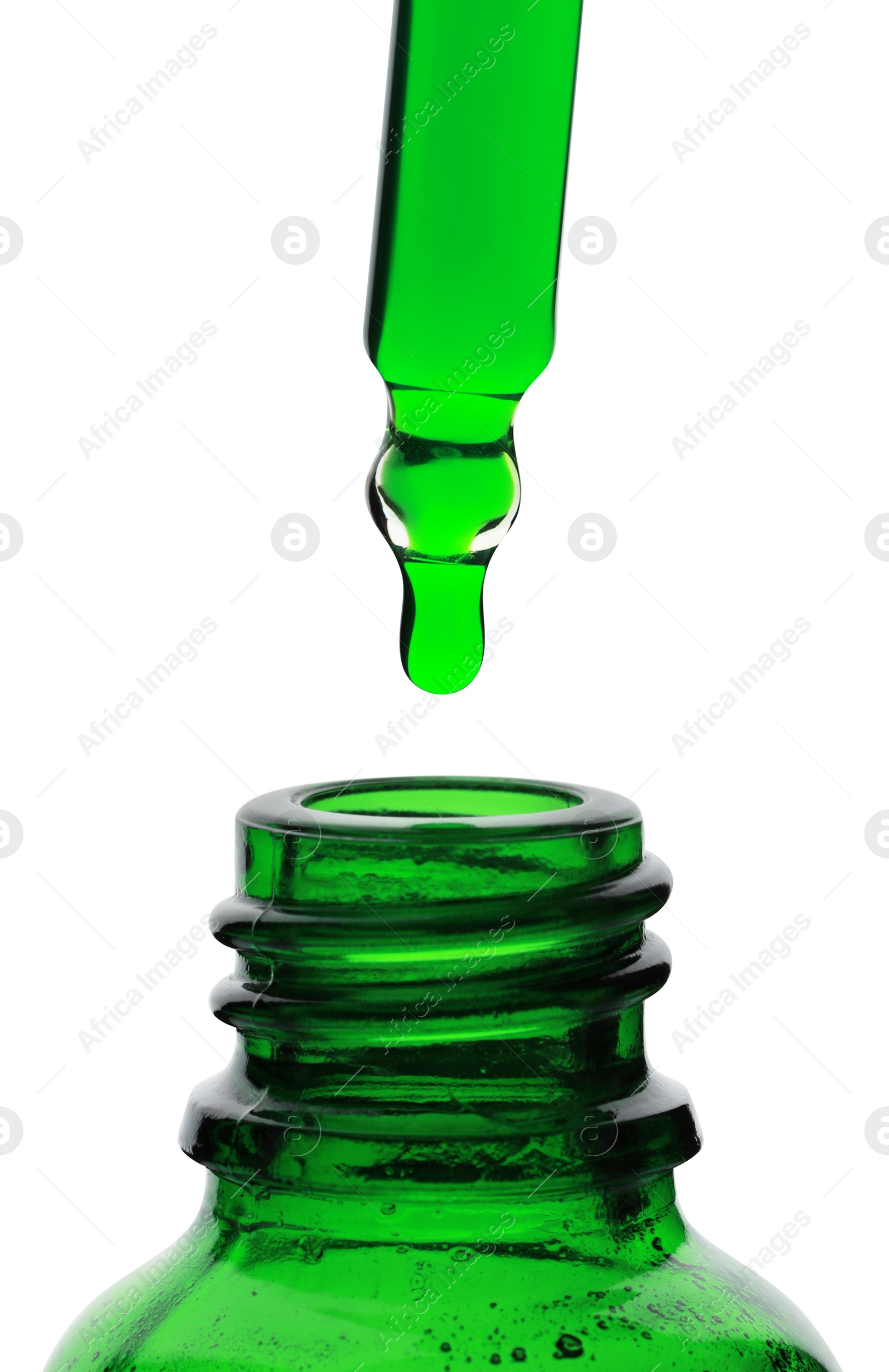 Photo of Dripping green facial serum from pipette into glass bottle on white background, closeup