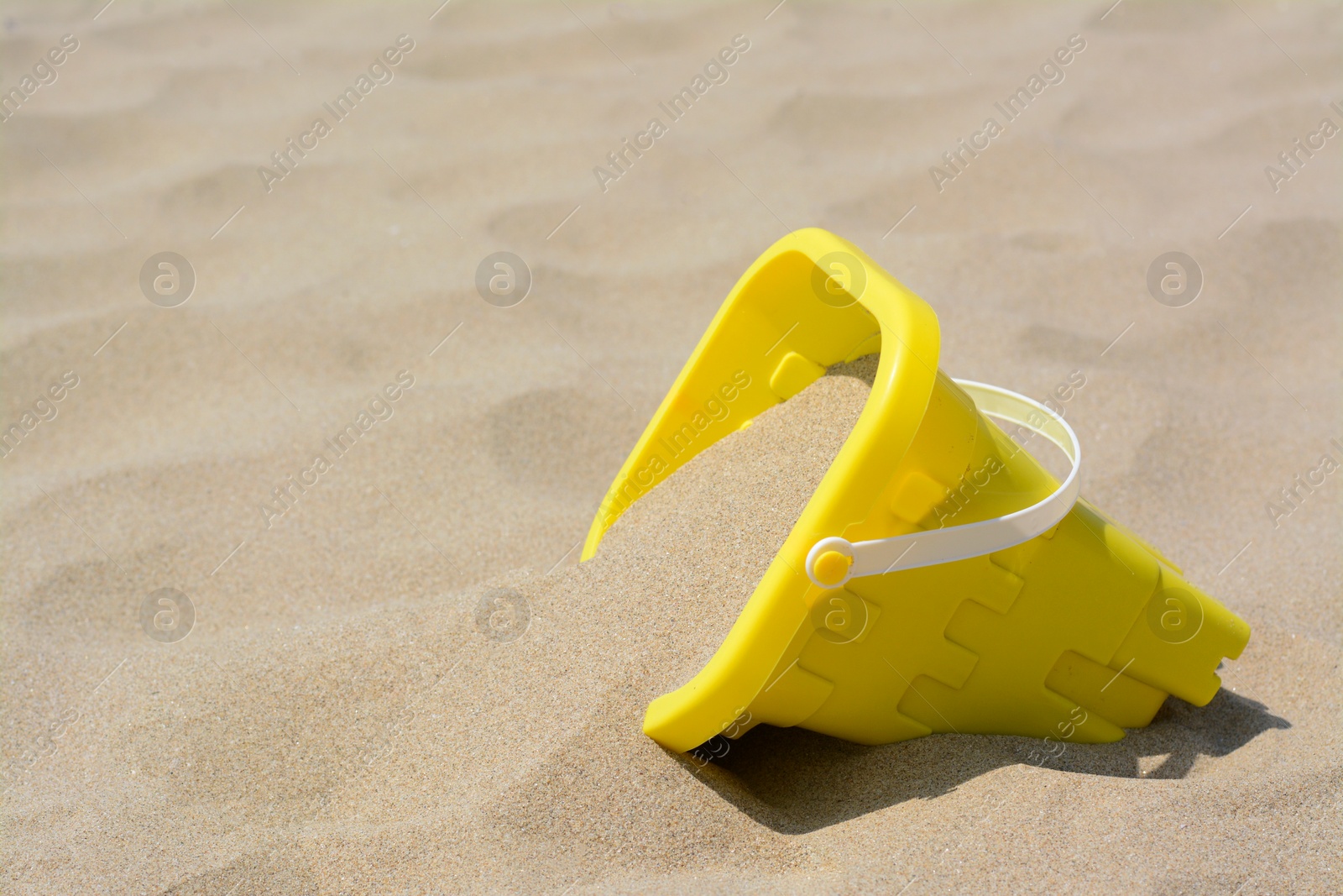 Photo of Yellow plastic bucket on sand, space for text. Beach toy