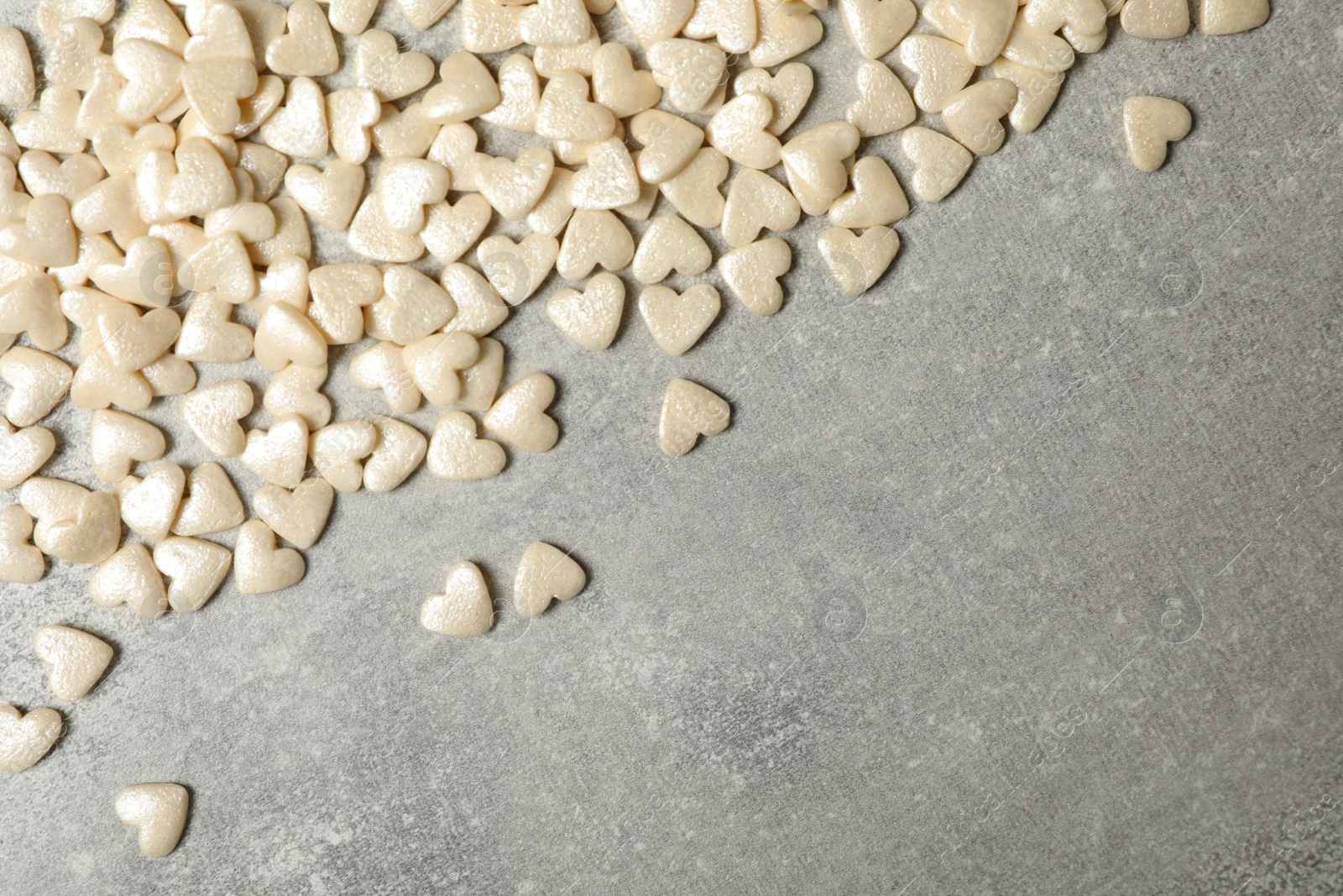 Photo of White heart shaped sprinkles on grey table, flat lay. Space for text