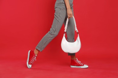 Woman with stylish bag on red background, closeup