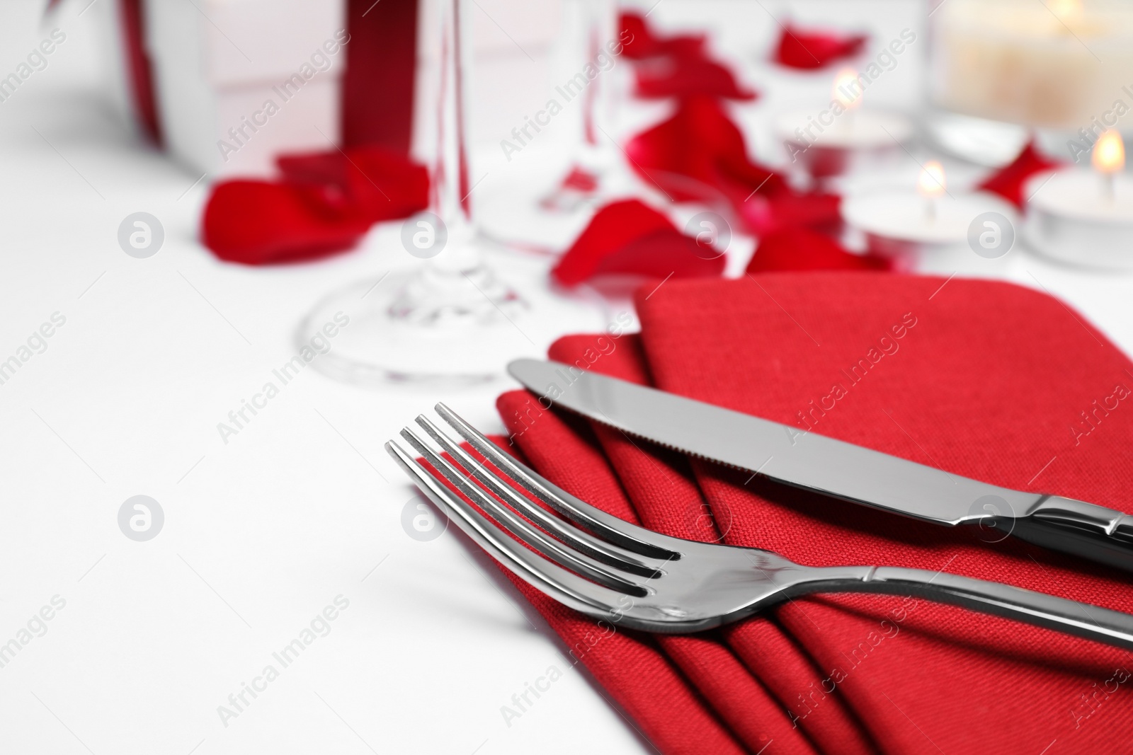 Photo of Beautiful table setting with rose petals on white table, closeup. Romantic dinner