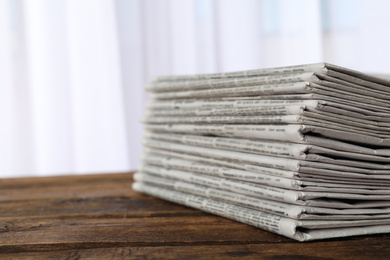 Stack of newspapers on wooden table, space for text. Journalist's work
