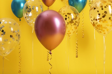 Bright balloons with ribbons on color background