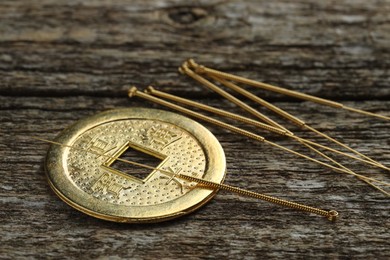 Photo of Acupuncture needles and Chinese coin on wooden table, closeup