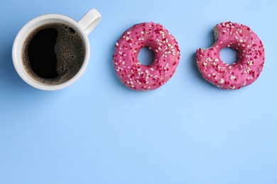 Tasty donuts and cup of coffee on light blue background, flat lay. Space for text