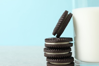 Photo of Chocolate sandwich cookies and glass of milk on color background, closeup. Space for text