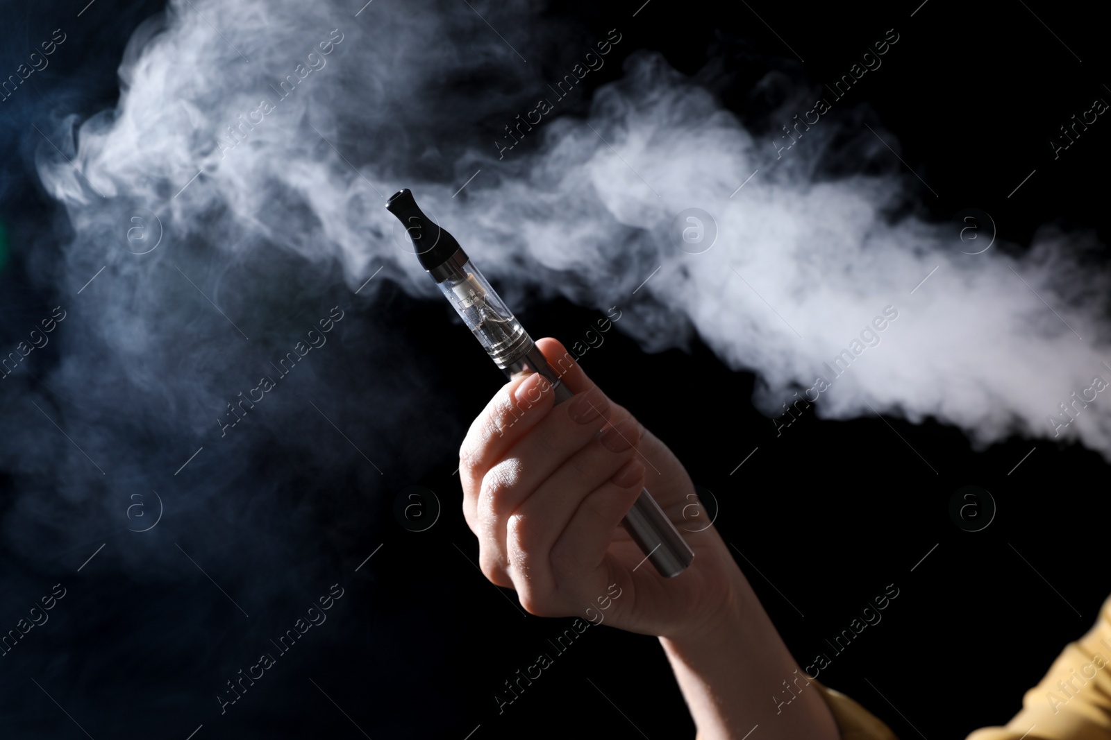 Photo of Woman holding electronic cigarette on black background, closeup