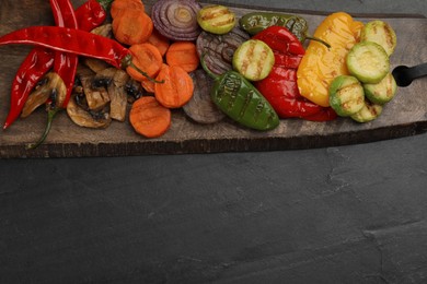 Photo of Delicious grilled vegetables on black table, top view. Space for text