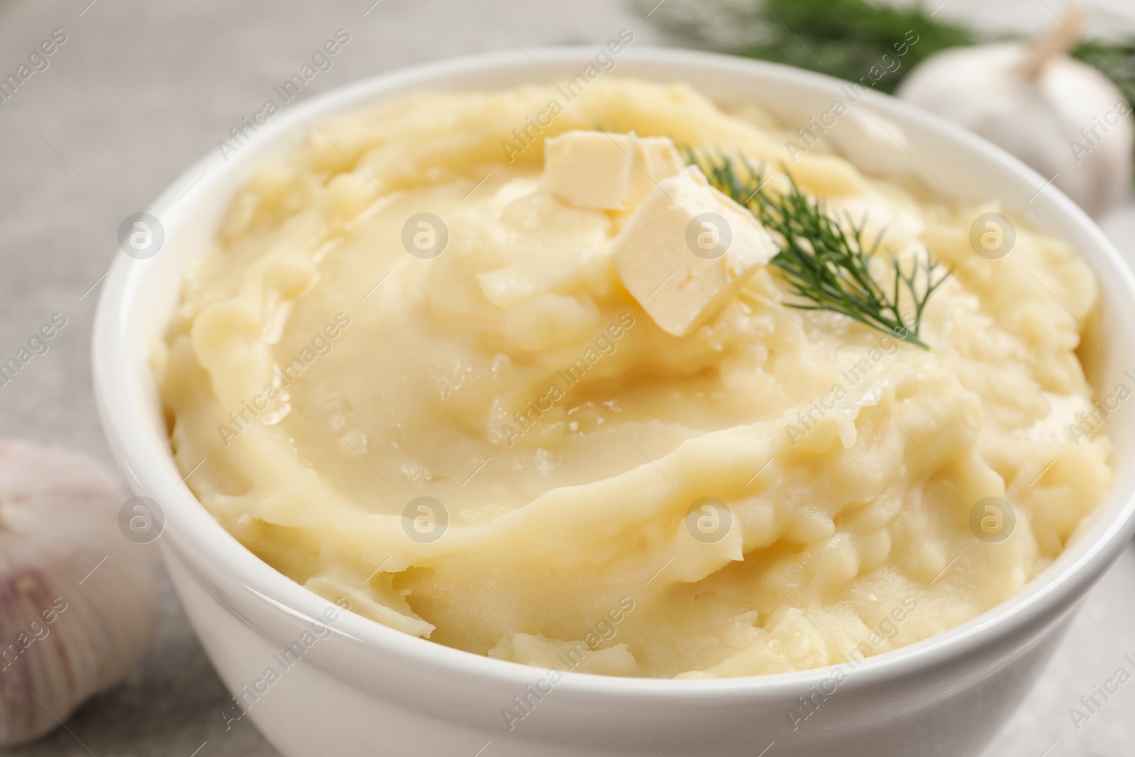 Photo of Bowl of delicious mashed potato with dill and butter, closeup