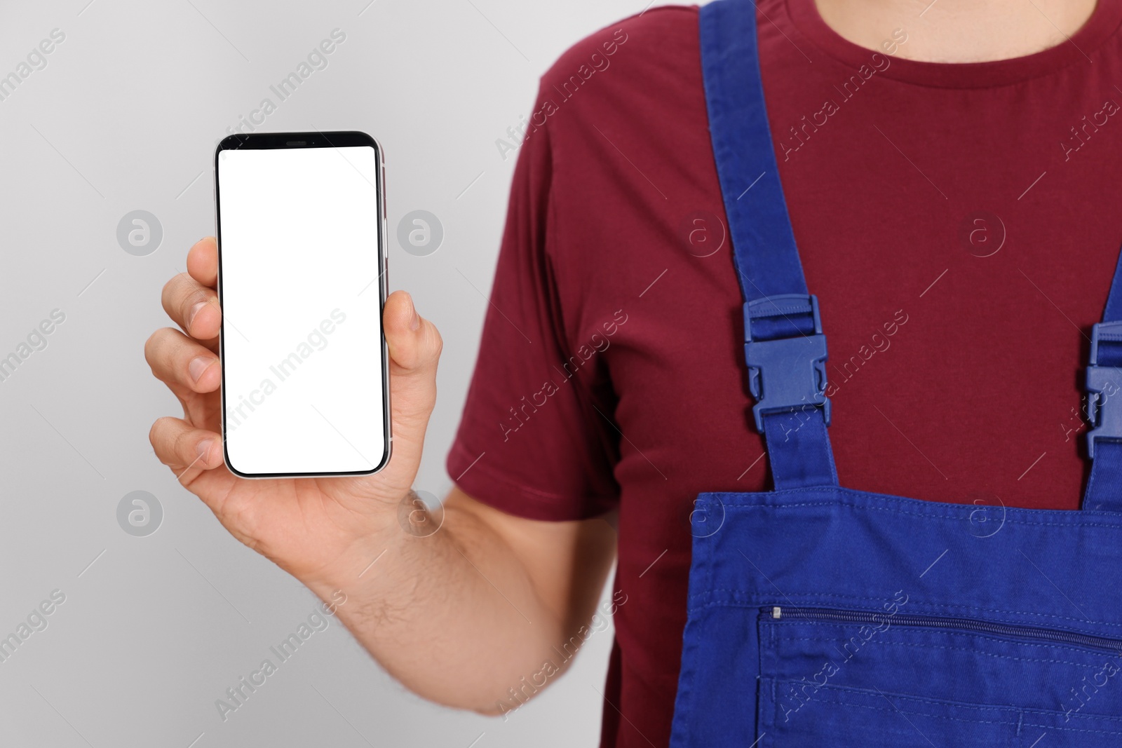 Photo of Professional repairman in uniform with phone on white background, closeup