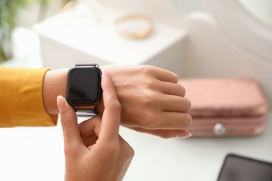 Image of Woman checking stylish smart watch at home, closeup