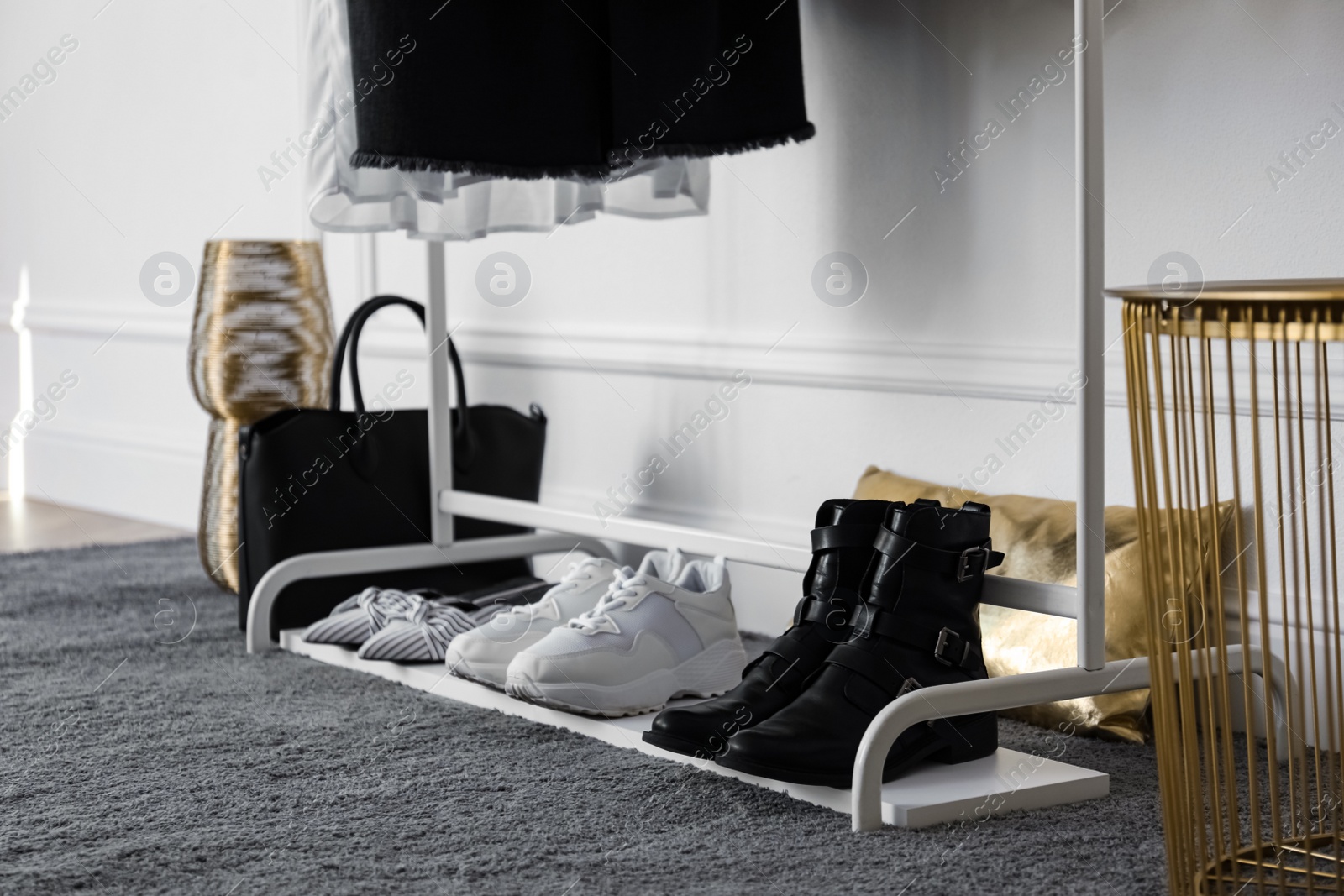 Photo of Rack with stylish clothes near white wall in dressing room