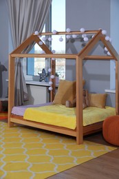 Photo of Stylish child room interior with comfortable house bed and toys