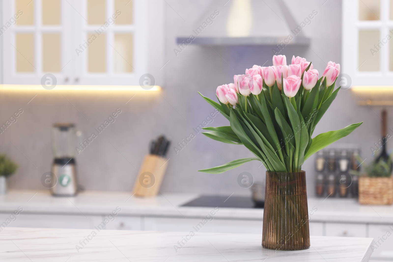Photo of Beautiful bouquet of fresh pink tulips on table in kitchen. Space for text