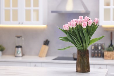 Beautiful bouquet of fresh pink tulips on table in kitchen. Space for text