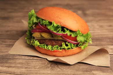 Photo of One tasty burger with vegetables, patty and lettuce on wooden table