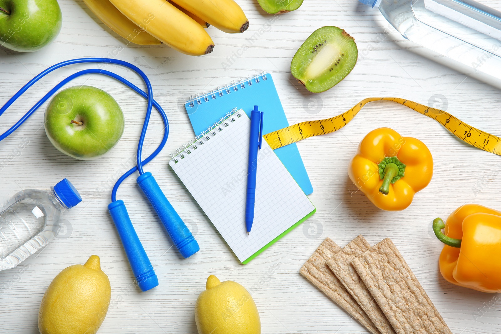 Photo of Flat lay composition with notebooks, healthy food and jumping rope on wooden background. Weight loss concept