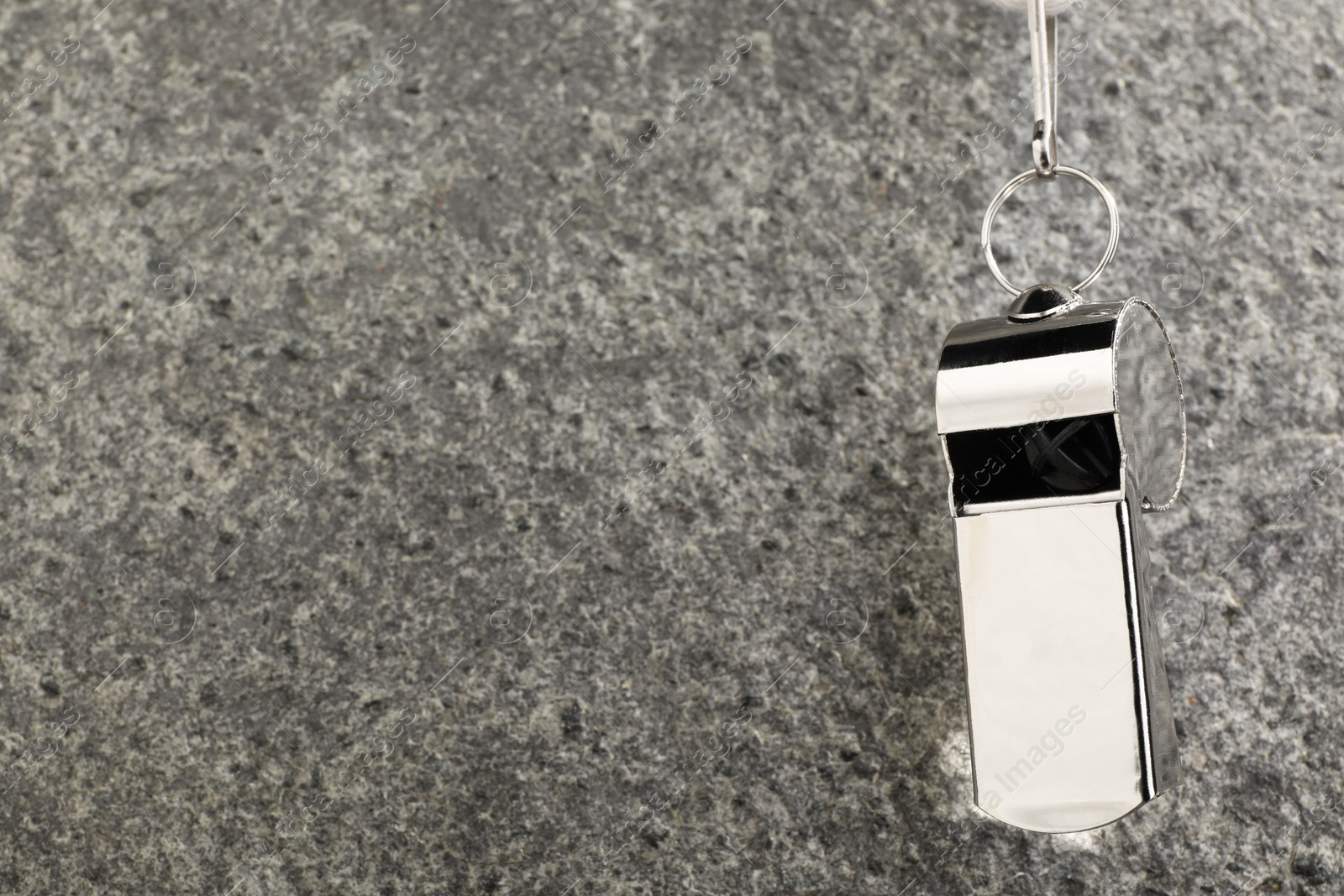 Photo of Referee equipment. Metal whistle on grey textured background, closeup and space for text