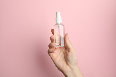 Photo of Woman holding antiseptic spray on pink background, closeup