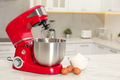 Photo of Modern red stand mixer, eggs and bowl with flour on white marble table in kitchen, space for text