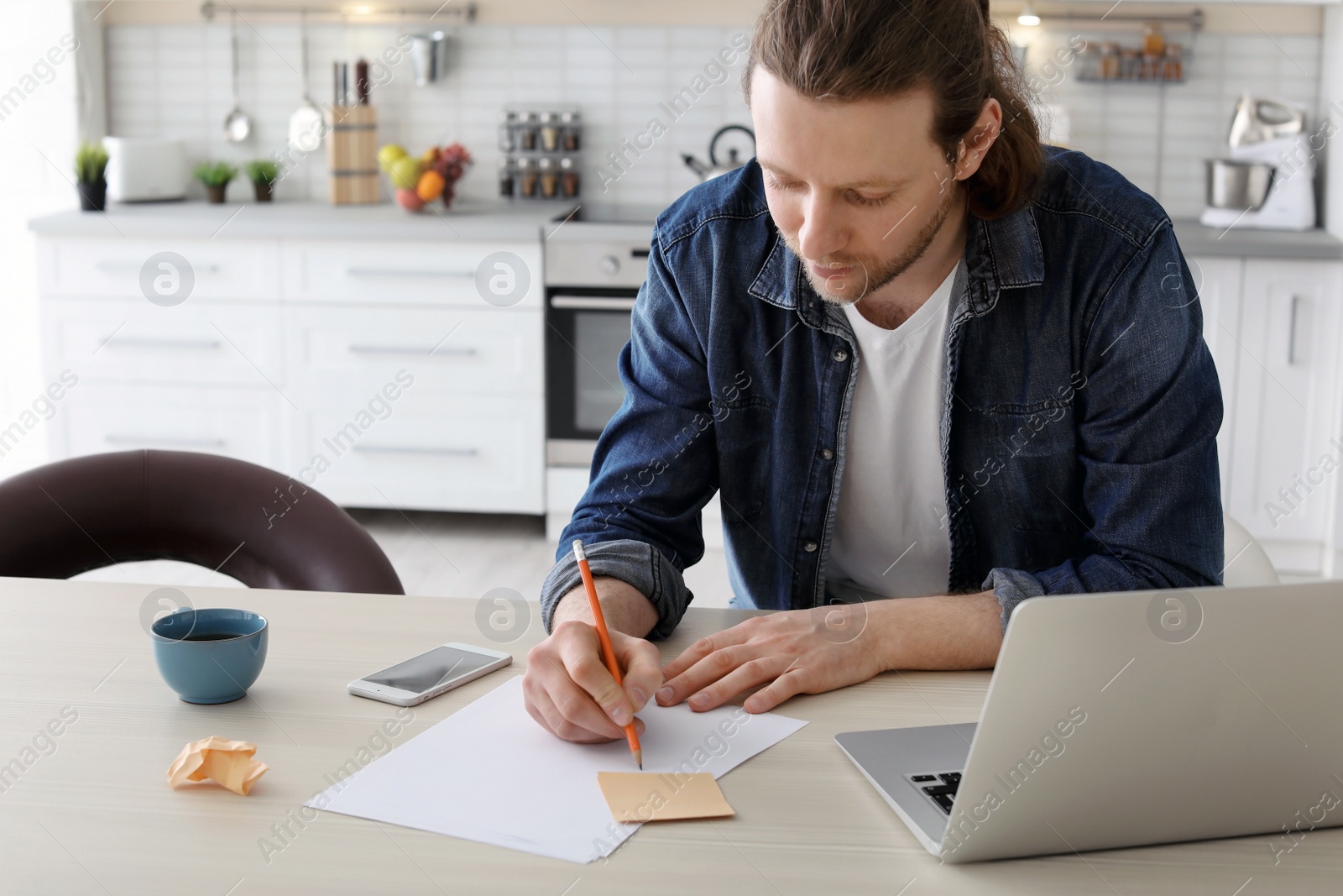 Photo of Young man working with laptop at desk in home office