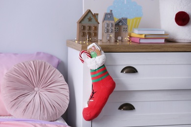 Photo of Stocking with presents hanging on drawer in children's room. Saint Nicholas Day tradition