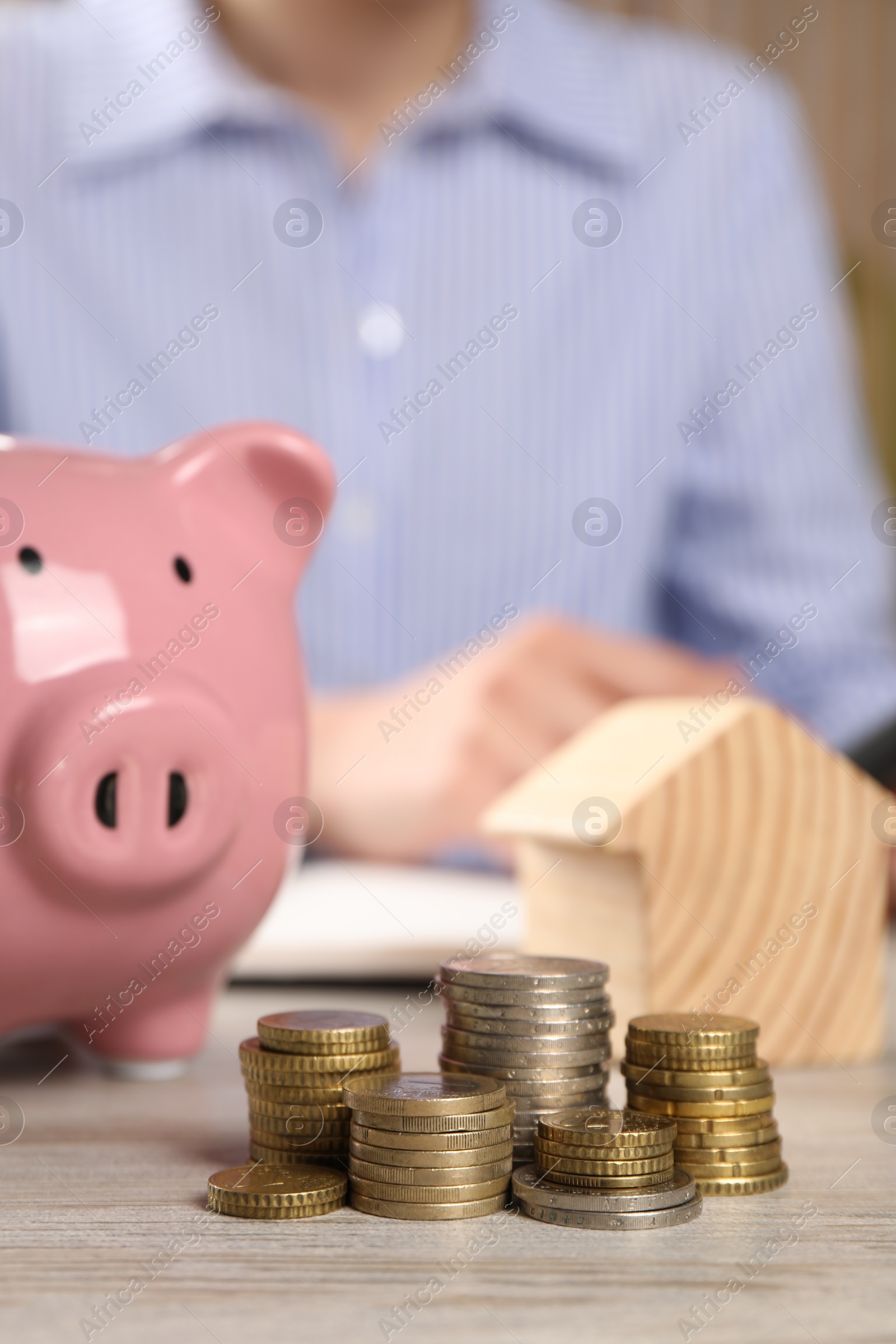 Photo of Savings for house purchase. Woman planning budget at wooden table, focus on coins