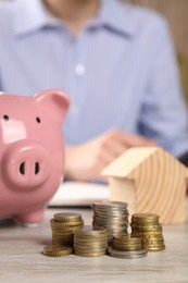 Photo of Savings for house purchase. Woman planning budget at wooden table, focus on coins