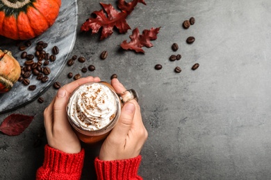 Photo of Woman with mason jar of tasty pumpkin spice latte at grey table, top view. Space for text