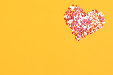 Photo of Heart made with shiny glitter on orange background, flat lay. Space for text