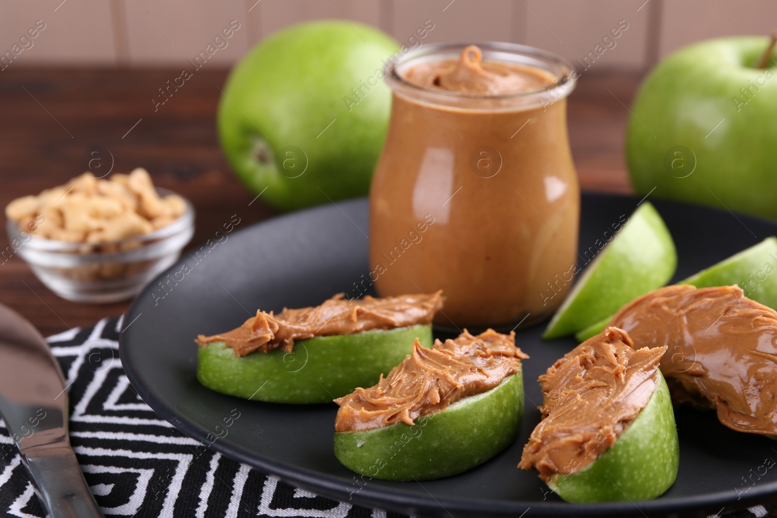 Photo of Slices of fresh green apple with peanut butter on table, closeup