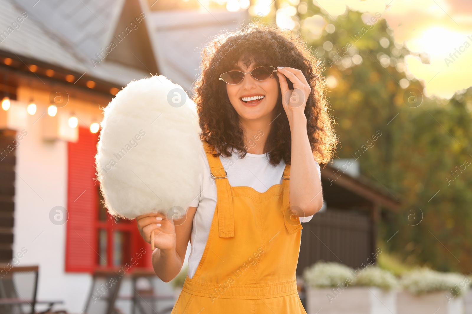 Photo of Portrait of happy woman with cotton candy outdoors on sunny day