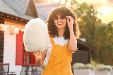 Photo of Portrait of happy woman with cotton candy outdoors on sunny day