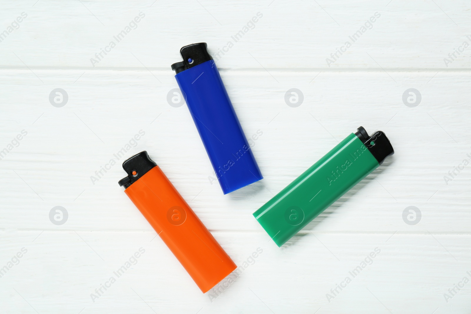 Photo of Stylish small pocket lighters on white wooden background, flat lay