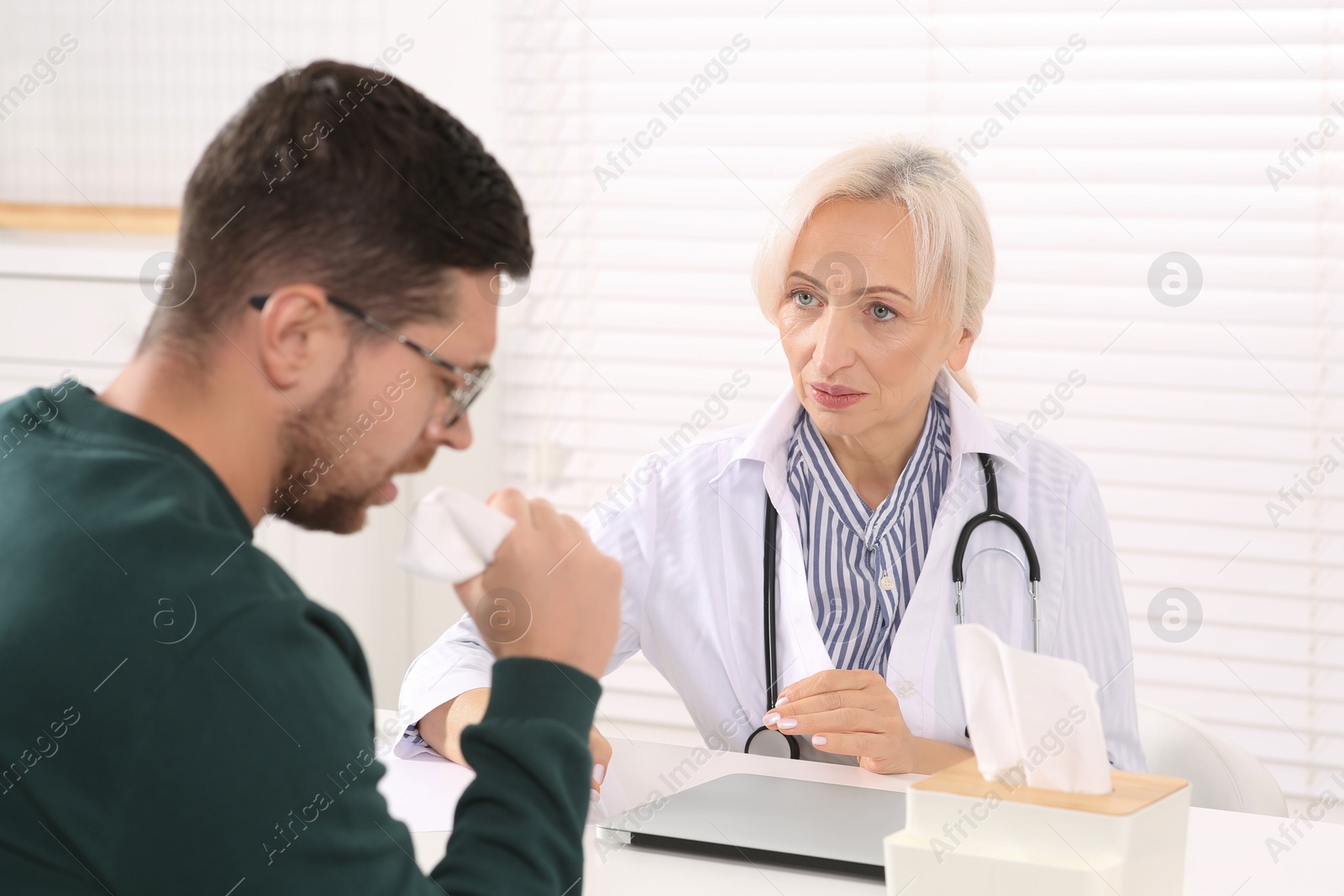 Photo of Sick patient with napkin and doctor at table in clinic