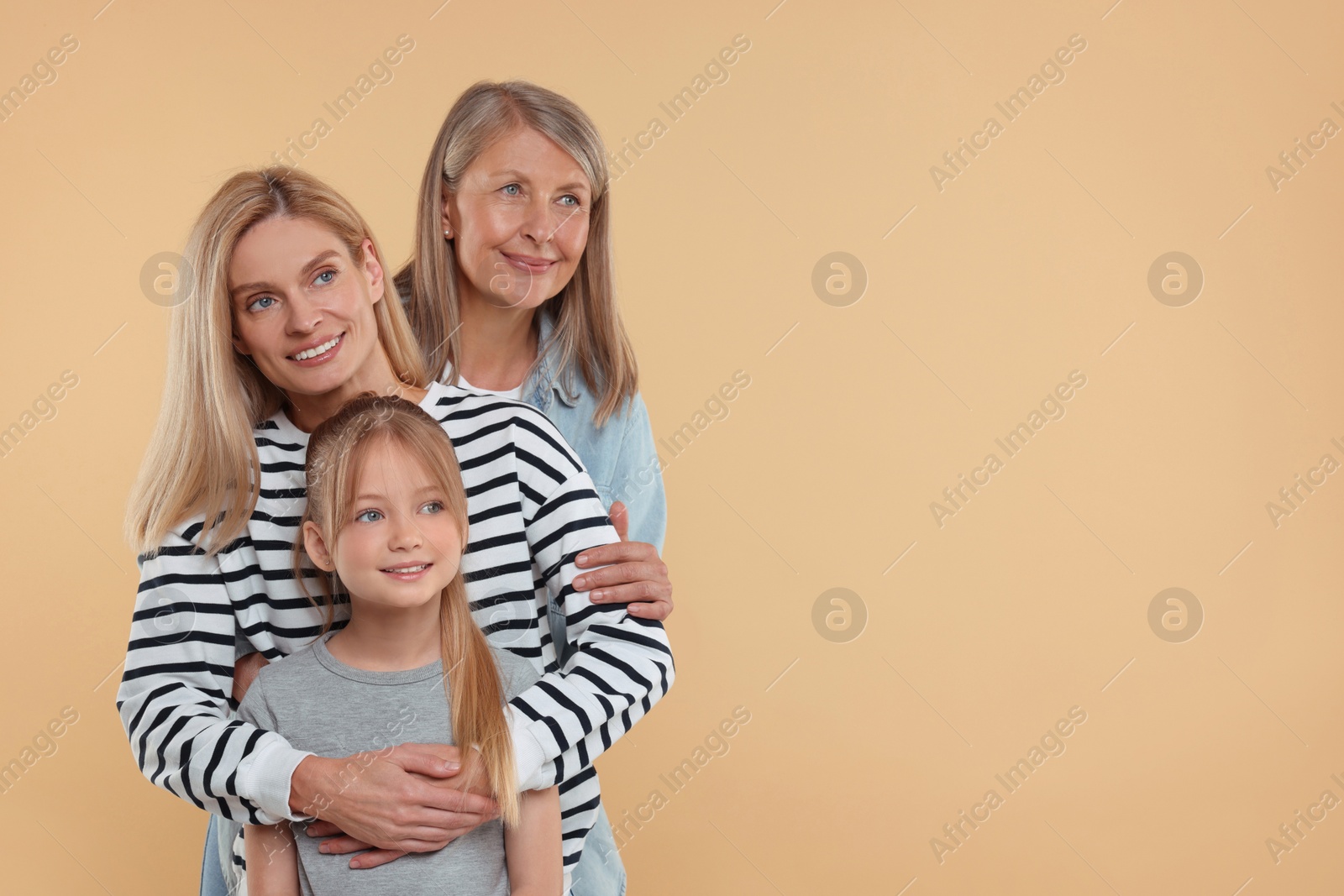 Photo of Three generations. Happy grandmother, her daughter and granddaughter on beige background, space for text