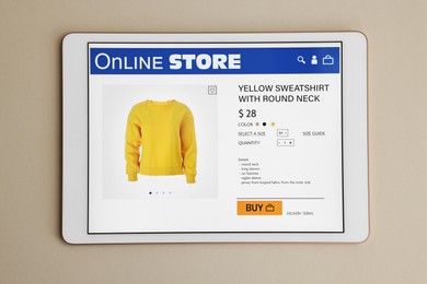 Photo of Modern tablet with open online store on beige background, top view