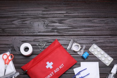 Flat lay composition with first aid kit on wooden table, space for text