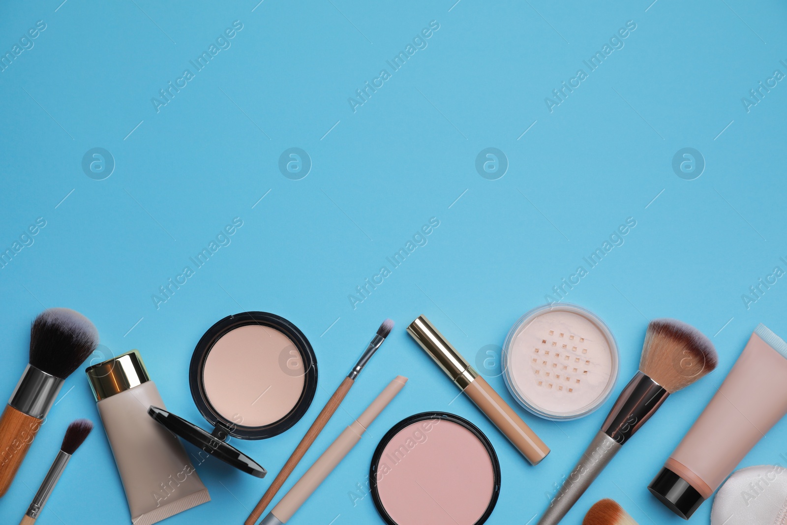 Photo of Face powders and other decorative cosmetic products on light blue background, flat lay. Space for text