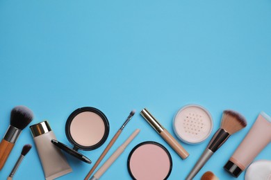 Photo of Face powders and other decorative cosmetic products on light blue background, flat lay. Space for text