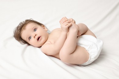 Photo of Cute baby in diaper lying on bed