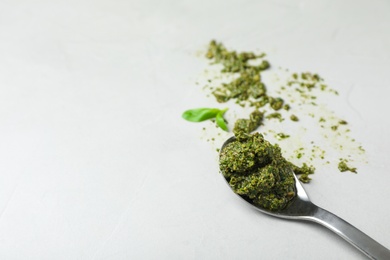 Photo of Spoon with basil pesto sauce and space for text on light background