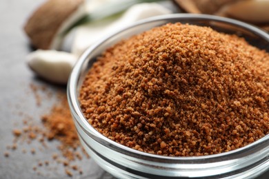 Photo of Natural coconut sugar in glass bowl on table, closeup