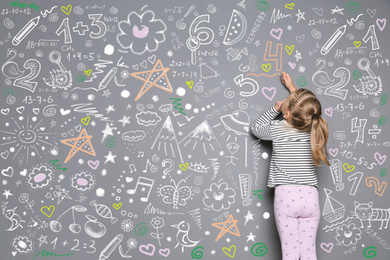 Image of Little child drawing with colorful chalk on gray wall