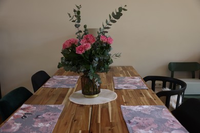 Beautiful bouquet of roses and napkins on wooden table indoors