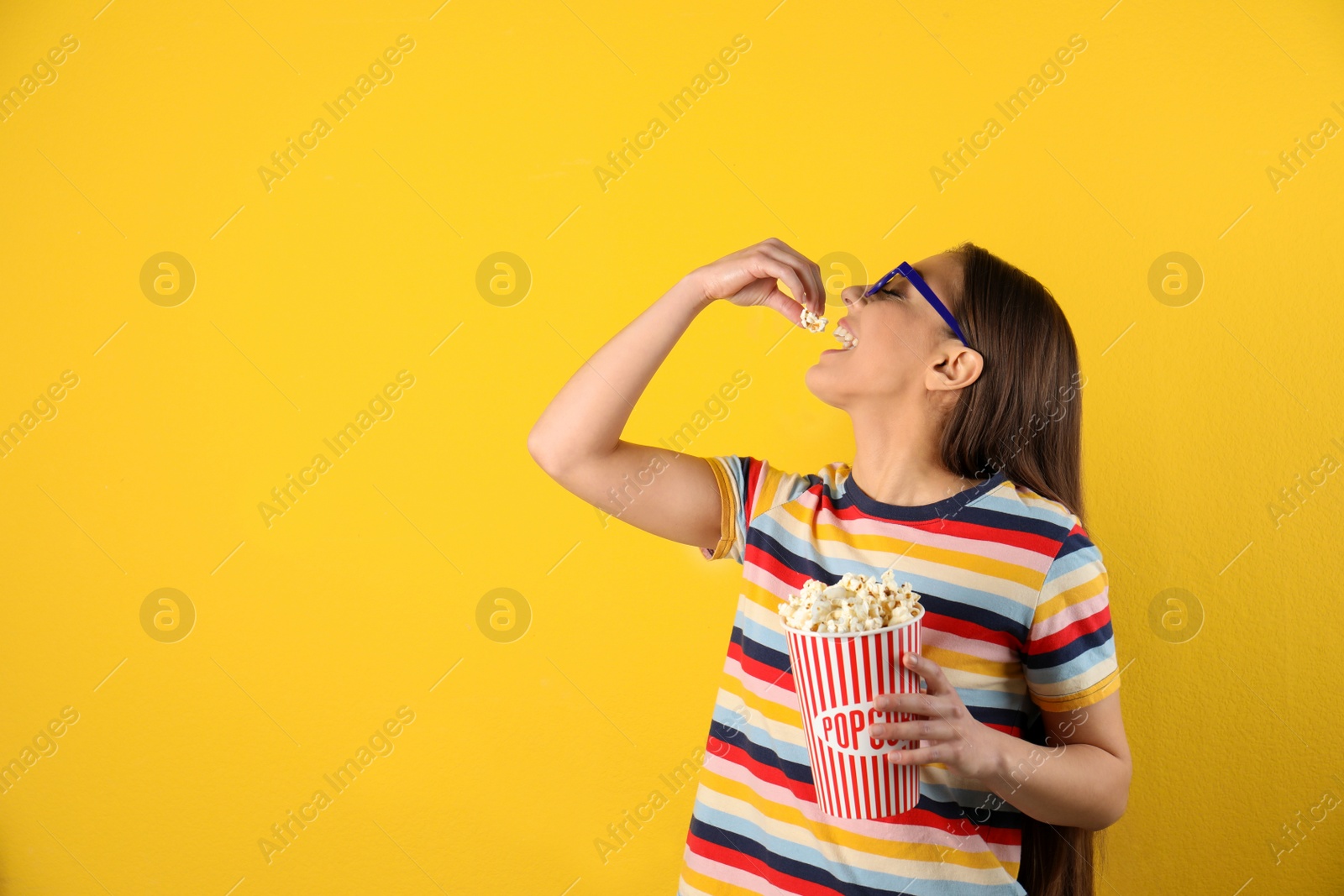 Photo of Young woman with 3D glasses eating tasty popcorn on color background. Space for text