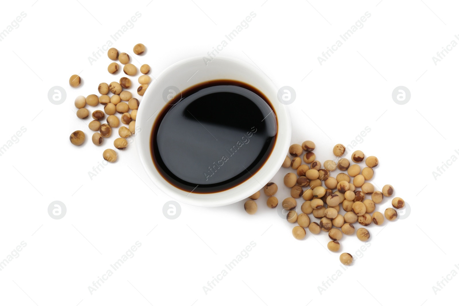 Photo of Tasty soy sauce in bowl and soybeans isolated on white, top view