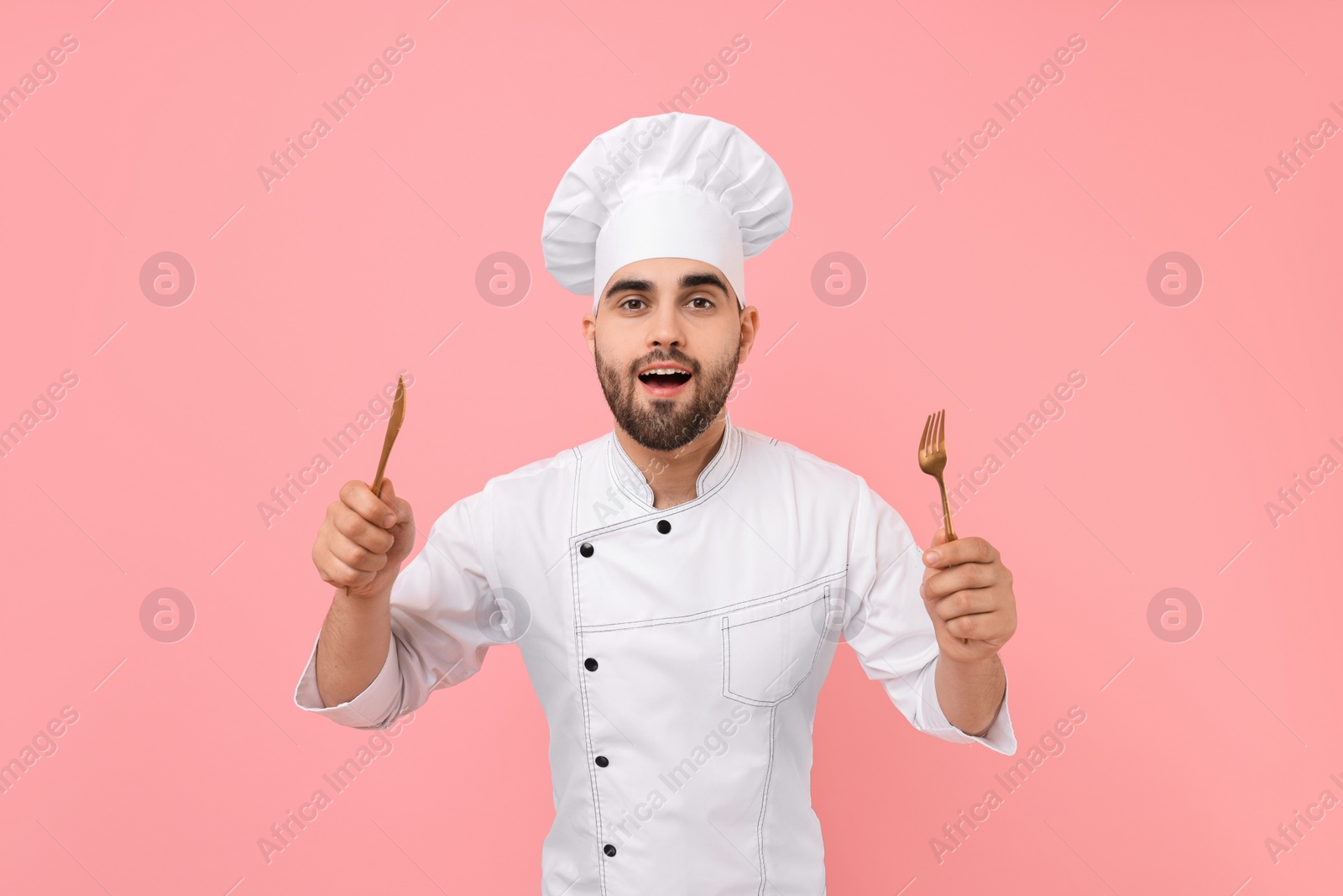 Photo of Professional chef holding kitchen utensils on pink background