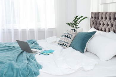 Photo of Laptop and books on bed in stylish room interior