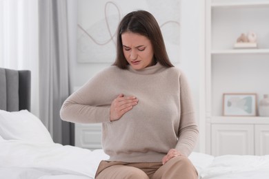 Photo of Mammology. Woman doing breast self-examination in bedroom